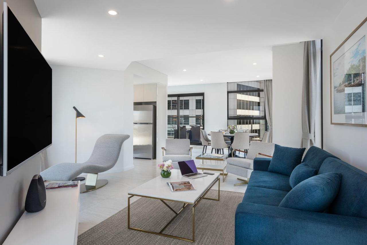 Meriton Suites Sussex Street, Sydney Zewnętrze zdjęcie The photo shows a modern living space that features a bright and stylish interior. Key elements include:

- A sleek blue sofa and a light gray lounge chair, providing comfortable seating.
- A coffee table with a minimalist design, positioned in front